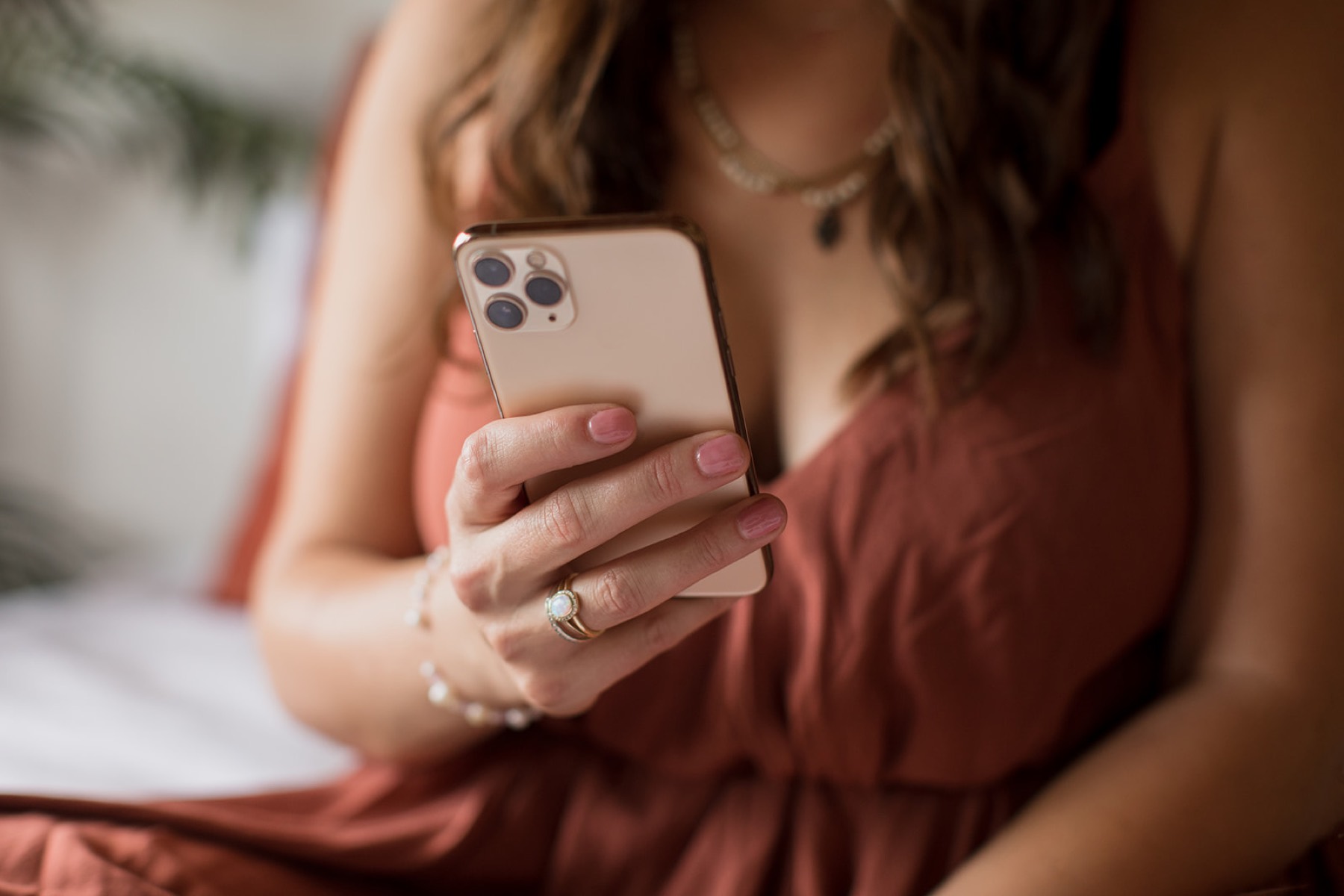 Heather Flynn in a terracotta dress, phone in hand, in a softly lit room