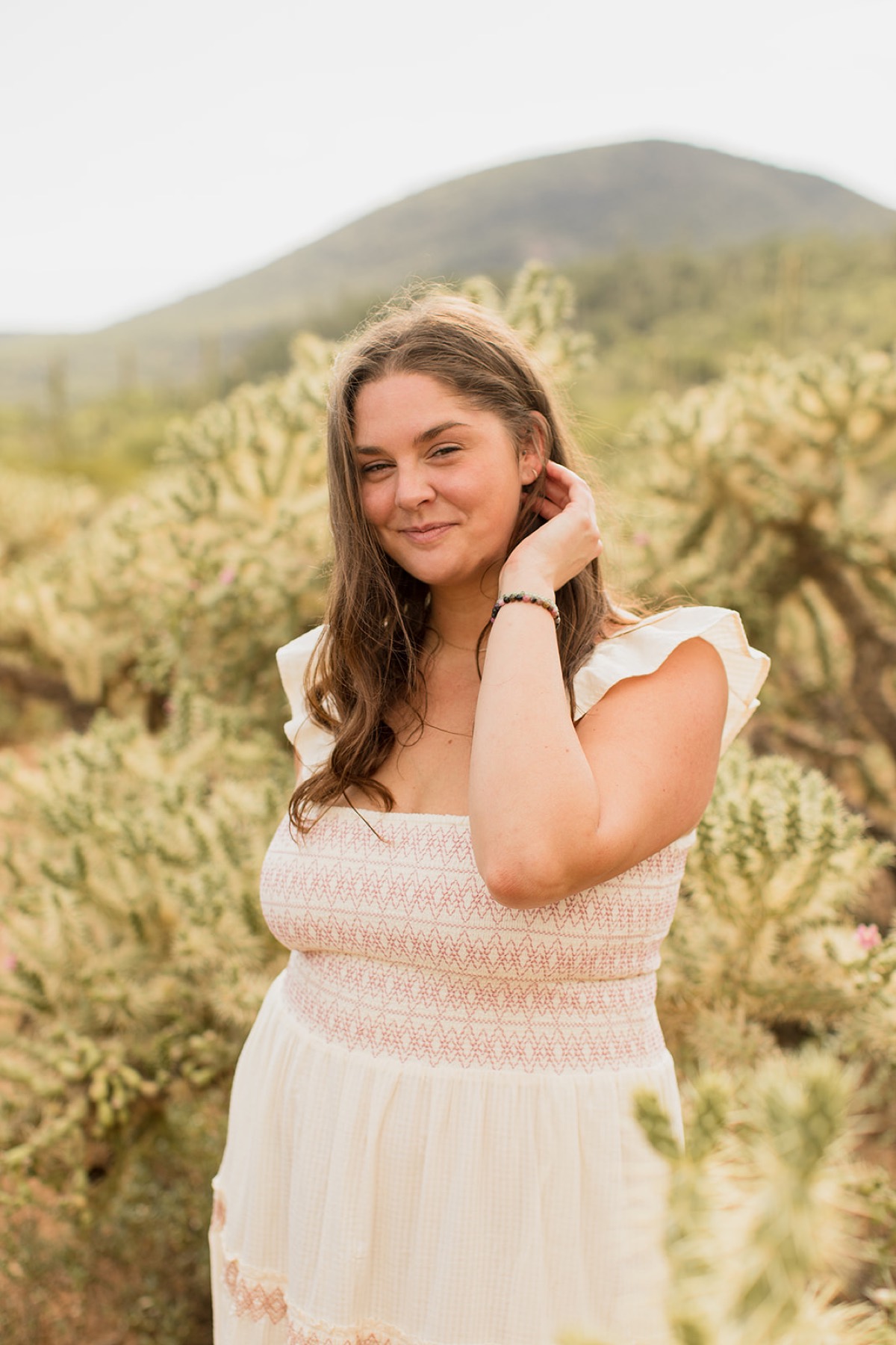 Heather Flynn in a white dress standing among saguaro cacti in the desert